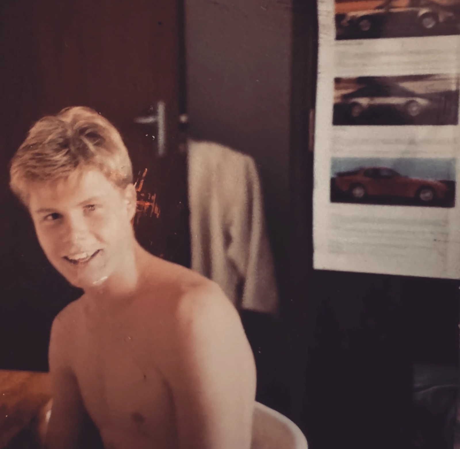 A young Lee Powell beside the wardrobe door covered in Porsche posters