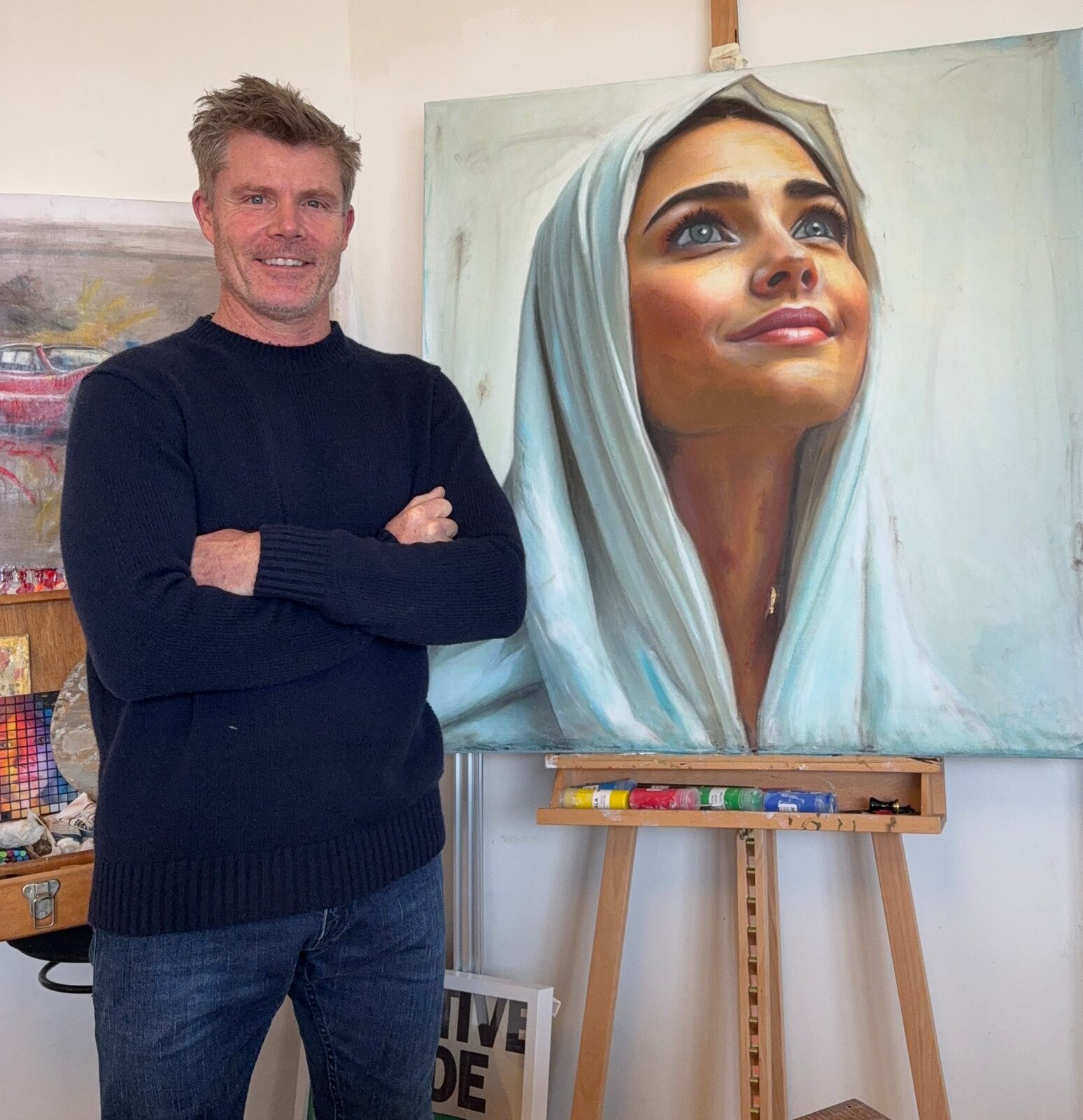 Lee Powell in the studio beside Lady in Waiting, a portrait of a woman in a pale headscarf looking upward
