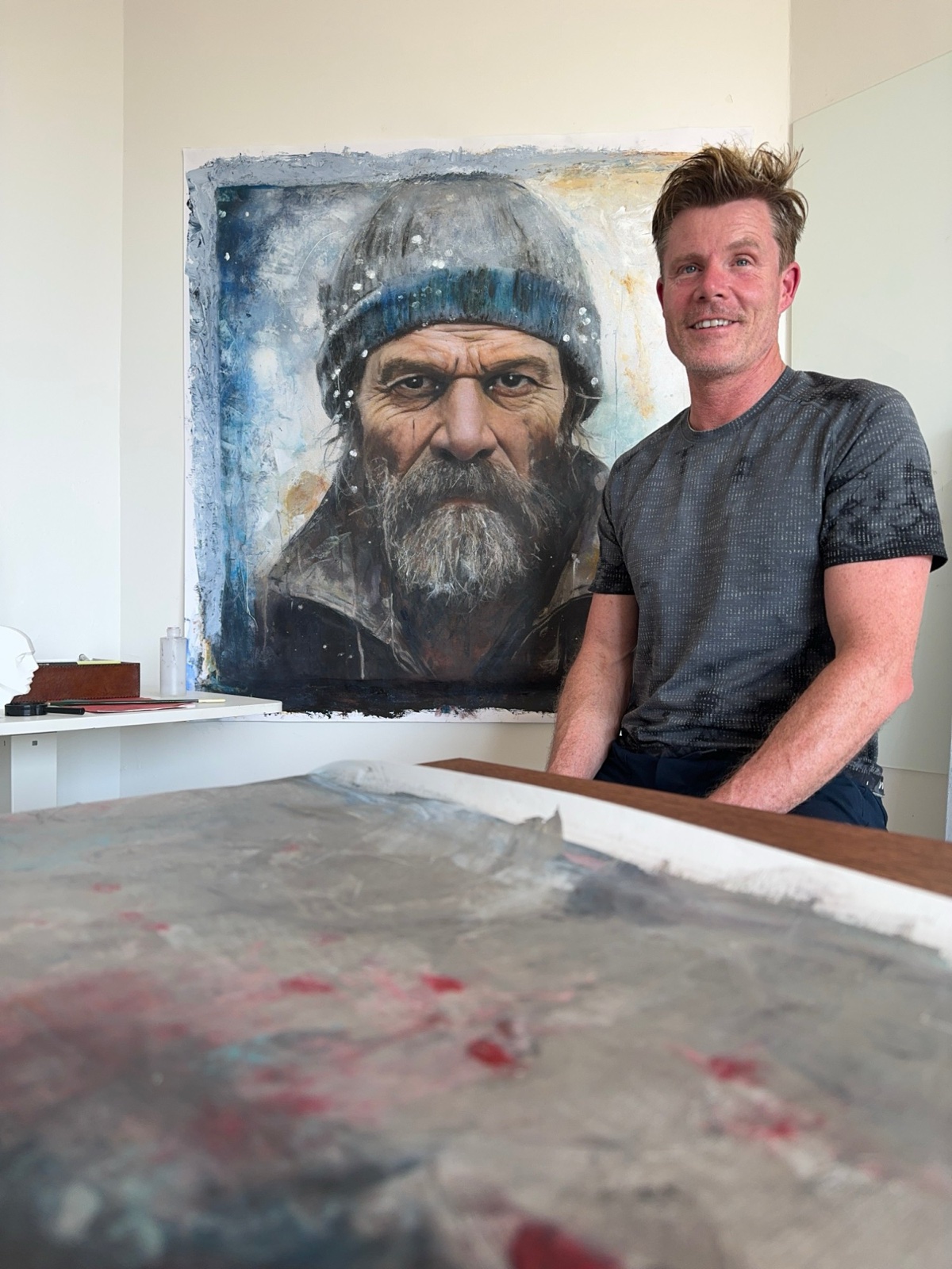 Keny in the St Kilda studio with a portrait of Wim Hof and an abstract in progress